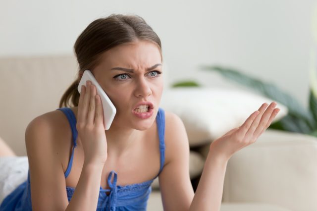Mujer joven enojada discutiendo por teléfono en casa